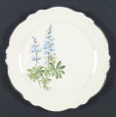 a white plate with blue flowers painted on the front and bottom, sitting on a black surface