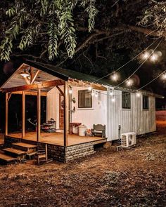 a tiny house with lights strung from the roof and porch on it's side