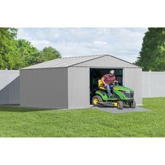 a man on a lawn mower in front of a storage shed with the door open