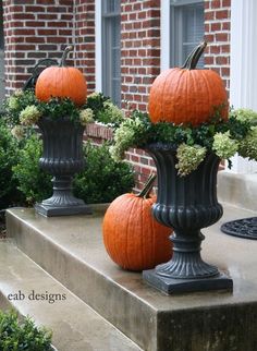 three pumpkins are sitting on top of the planters in front of a building