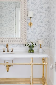 a bathroom with a sink, mirror and gold faucet