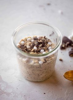 a glass jar filled with food sitting on top of a table next to a spoon