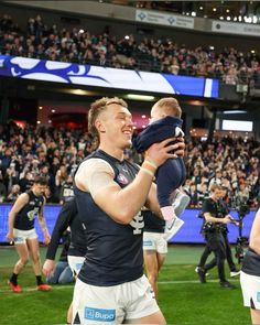 a man holding a baby in front of a crowd