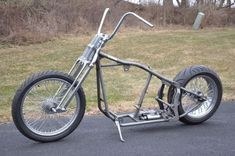 an unusual looking motorcycle is parked on the side of the road in front of some grass