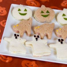 there are some cookies shaped like ghostes on a white plate with pumpkins and jack - o'- lanterns in the background