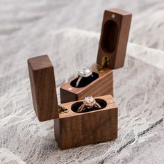 two wooden boxes with wedding rings inside on a lace tablecloth covered surface, one containing an engagement ring and the other holding a diamond