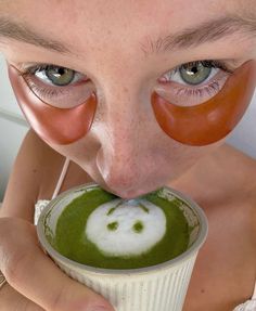 a person with fake tomatoes on their faces sticking out of a cup filled with green liquid