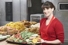 a woman standing in front of trays of food