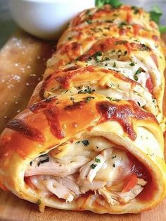 a wooden cutting board topped with an enchilada covered in meat and cheese