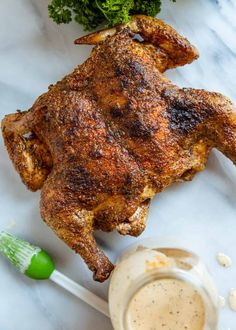 a piece of chicken on a table next to some broccoli and sauces