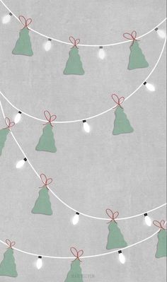 christmas trees with lights and bows are hanging on a string in front of a gray wall