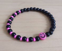 a black and pink beaded bracelet with a smiley face