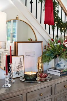 a christmas scene with candles and pictures on a dresser in front of the banister