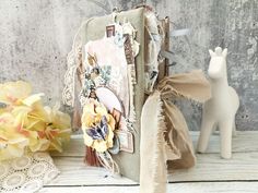 an altered book is sitting on a table next to some flowers and a white horse