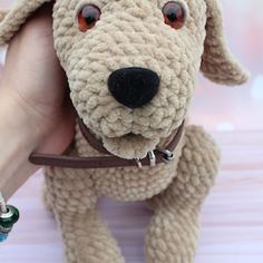 a stuffed dog is being held by a person's hand and wearing a collar