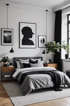 a bedroom with white walls, black and grey bedding and pictures on the wall