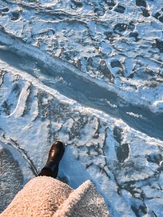 someone is standing in the snow with their feet propped up on some ice and water