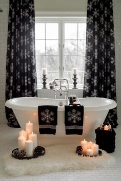 a white bath tub sitting under a window next to candles