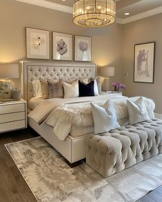 a large white bed sitting in a bedroom under a chandelier