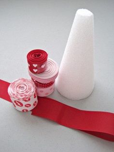 two rolls of red and white paper next to a roll of ribbon on a table