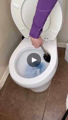 a person using a plunger to clean a toilet