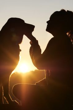 the silhouette of a woman and her dog at sunset