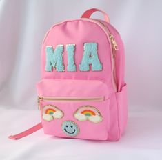 "High Quality Nylon Mini Backpack with your own Personal Touch! Nylon Waterproof Gold Hardware Bag is 12\" tall x 8.5\" wide x 4\" deep Polyester lining inside. Patches are High Quality Glued on or Self-Adhesive. Some patches may be hand stitched for added durability. Choose any Color and Patch Combination! Color Options Include: Baby Pink, Hot Pink, Salmon, Baby Blue, Violet, Mint Patch Options Include: Letters, Heart, Smiley Face, Rainbow, Palm Tree, Anchor, Lightning Bolt, Stars, Minnie Mouse Stony Clover Backpack, Pink School Bag With Letter Patch, Pink School Bags With Letter Patch, Backpack With Patches, Heart Smiley, Back To School Bag, Combination Color, Varsity Letters, Packing Bags Travel