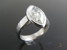 a close up of a diamond ring on a black surface with the reflection of it