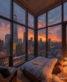 a bedroom with large windows and a view of the city at sunset or dawn,