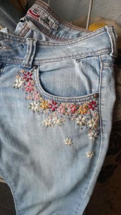 an old pair of jeans with embroidered flowers on them