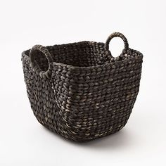 a large woven basket with handles on a white background, it is dark brown and has an oval handle