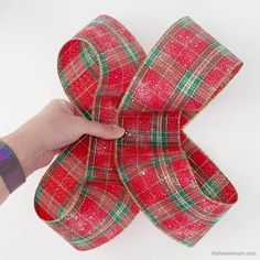 a hand holding a red and green plaid ribbon