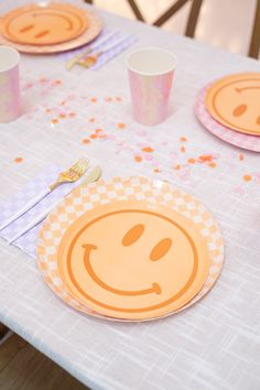 a table topped with plates and cups filled with confetti on top of it