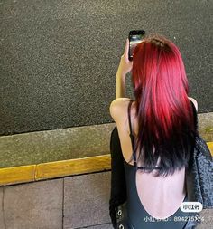 a woman with red hair taking a selfie in front of a wall holding a cell phone