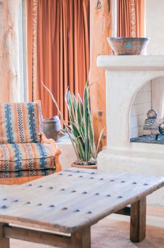 a living room filled with furniture and a fire place in front of a window next to a potted plant