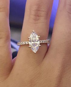 a woman's hand with a diamond ring on top of her finger and an engagement band