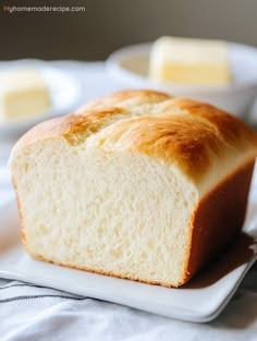 a loaf of bread sitting on top of a white plate next to butter cubes