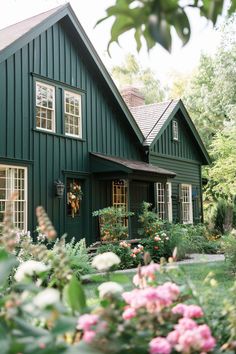 a green house with lots of flowers in the front yard