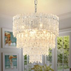 a crystal chandelier hanging from the ceiling in a room with pictures on the wall