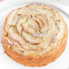 a white plate topped with a pastry covered in powdered sugar and apple slices on top of it