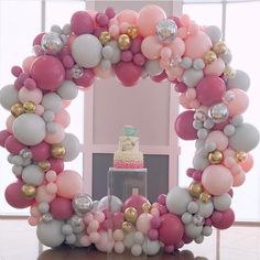 a birthday cake is surrounded by balloons in the shape of a wreath on top of a table