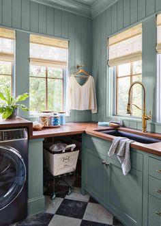 a washer and dryer in a small kitchen with blue walls, wooden counter tops and cabinets