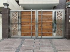 a large metal gate with wooden panels and decorative designs on the sides, in front of a building