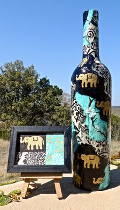 an elephant themed bottle is next to a painting and framed picture on easel stand