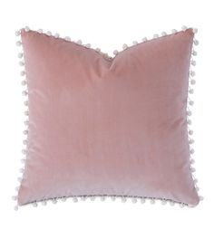 a pink pillow with pom - poms on it