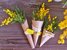 three paper cones with yellow flowers tied to them