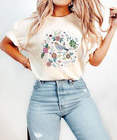 a woman wearing ripped jeans and a t - shirt with a bird on the front