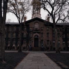 an old brick building with a clock tower in the middle of it's front yard