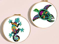 two cross stitch hoop paintings depicting lizards and a turtle