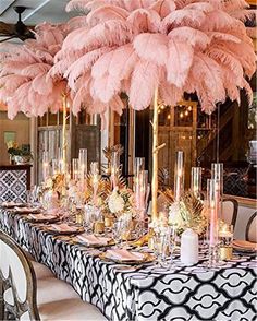 the table is set with pink feathers and candles